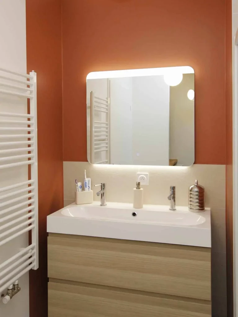 meuble de salle de bain double vasque avec mur terracotta et miroir rétroéclairé pensé par une architecte d'intérieur des hauts-de-seine
