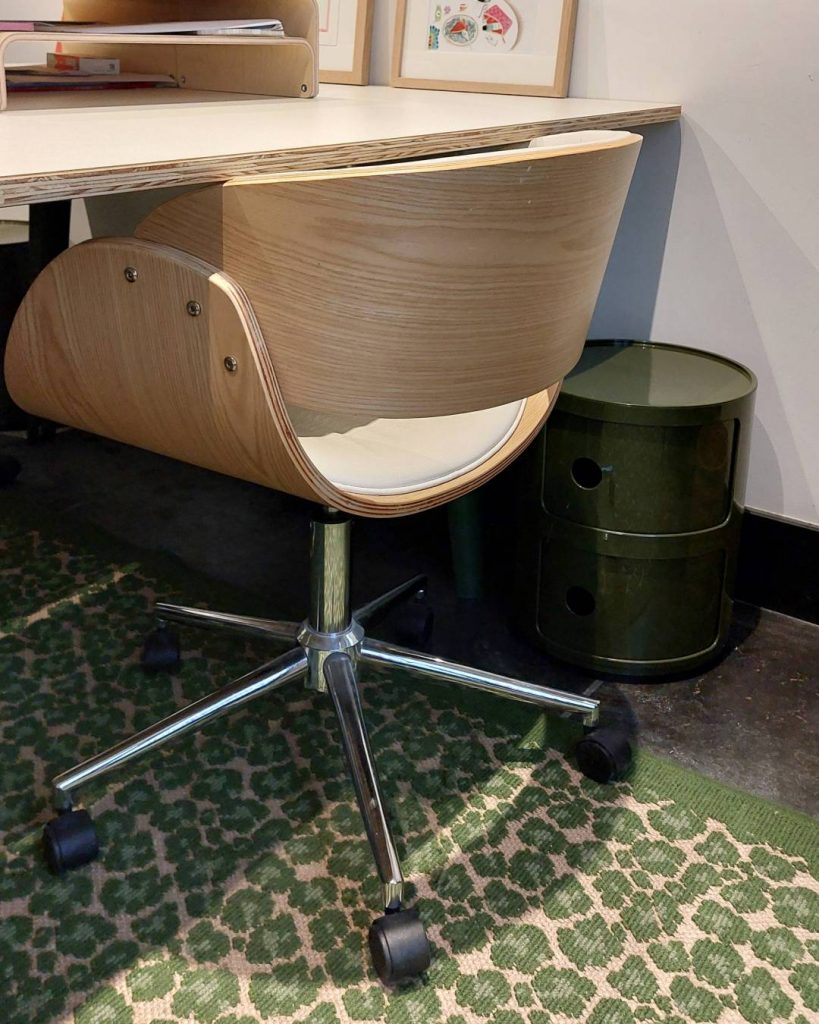 Détails d'un bureau avec tapis léopard, caisson vert et meubles en bois et blanc