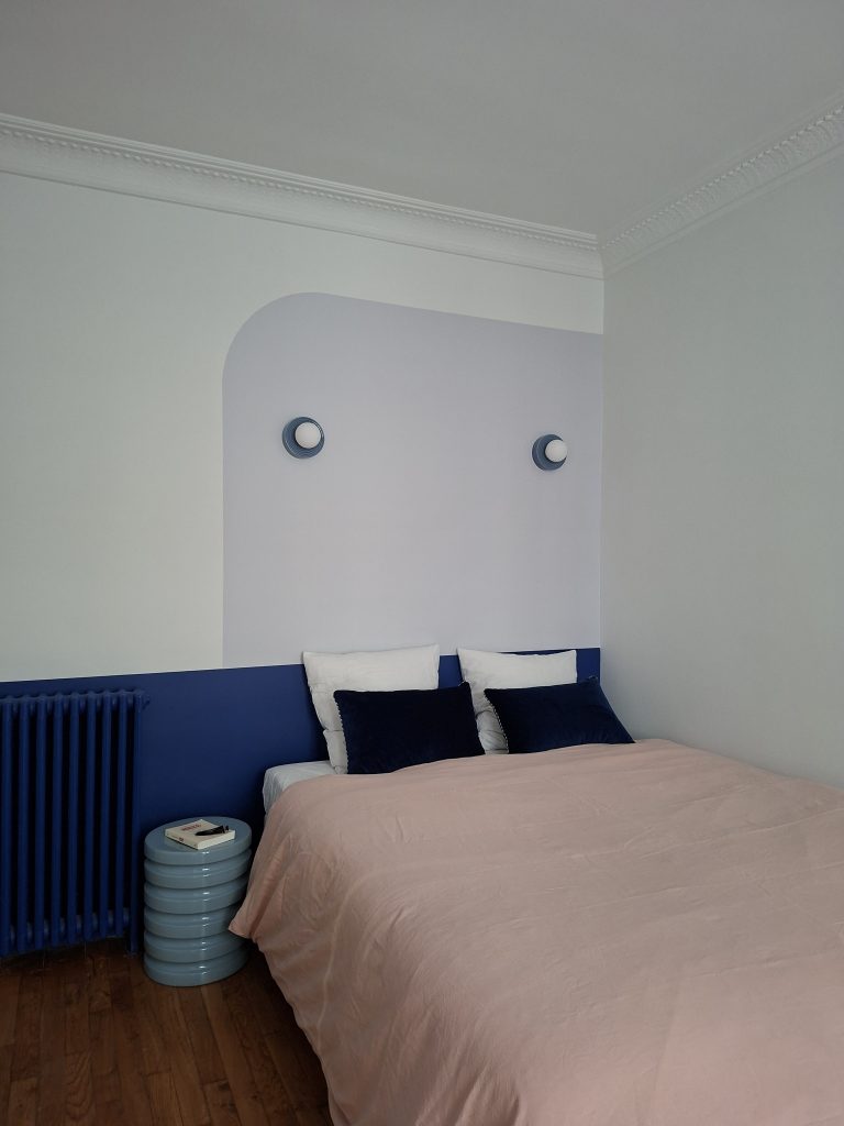 Tête de lit bleu et draps vieux rose dans chambre double avec tête de lit peinte