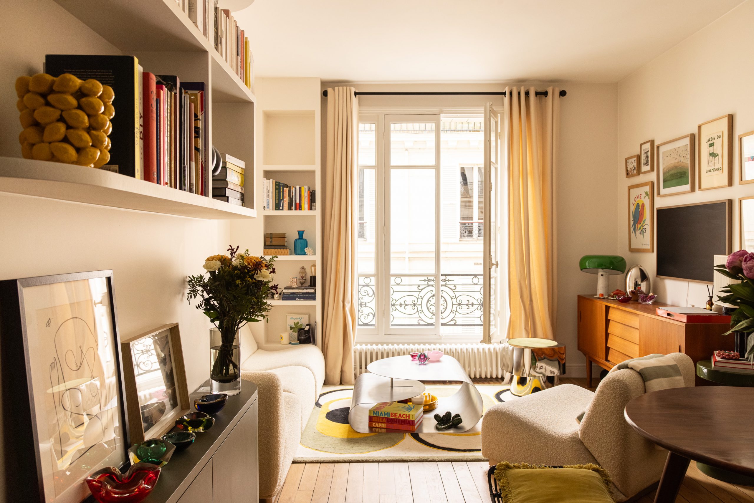 volume du séjour aggrandi pour accueillir un canapé à proximité de niches décoratives, une TV murale encadrés de tableaux, une banquette d'angle pour la salle à manger et une bibliothèque arrondie sur mesure