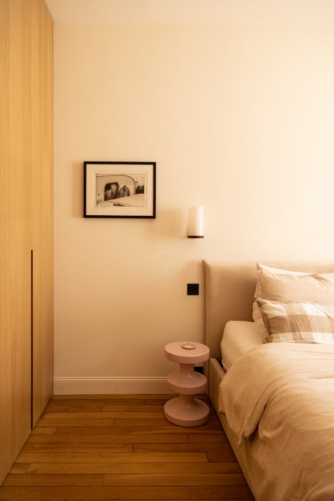 chambre parentale avec tête de lit beige, applique murale chinée, cadre décoratif et dressing sur mesure en chêne