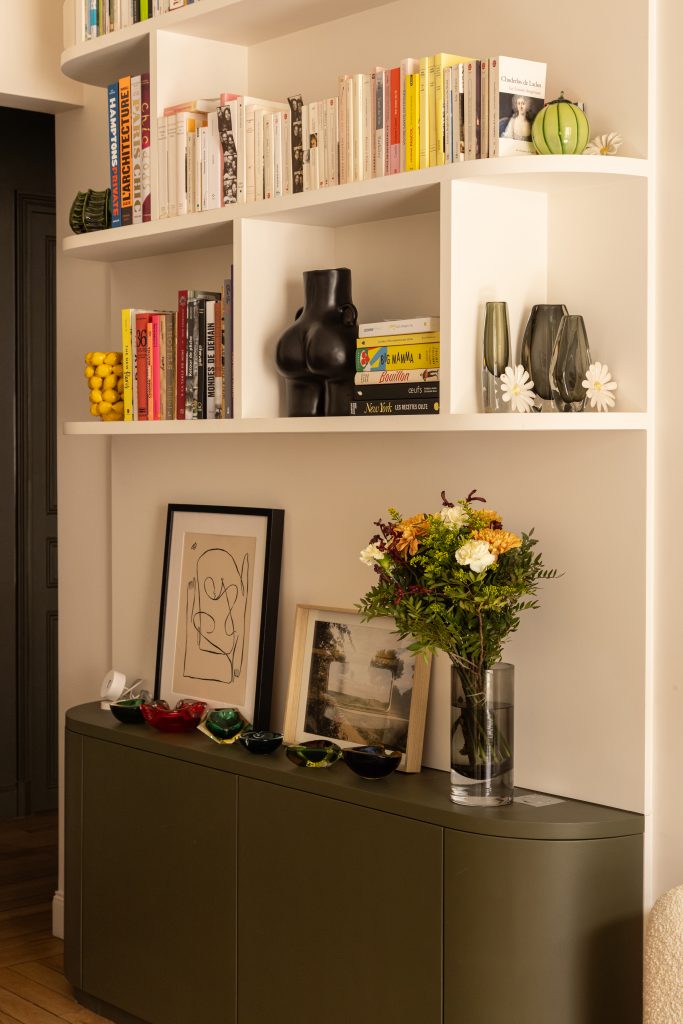 Bibliothèque sur mesure dessinée par une architecte d'intérieur. Partie basse à portes vert, espace décoratif au centre et étagères blanches aux angles arrondis en hauteur