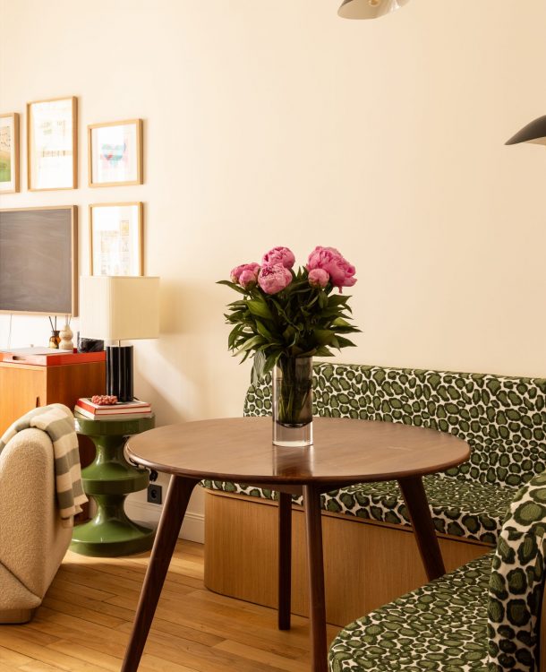 séjour avec coin salle à manger avec banquette d'angle et coussin vert léopard, parquet, table en noyer. A l'arrière le séjour ouvert
