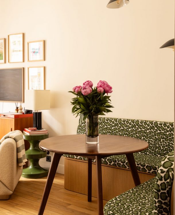séjour avec coin salle à manger avec banquette d'angle et coussin vert léopard, parquet, table en noyer. A l'arrière le séjour ouvert